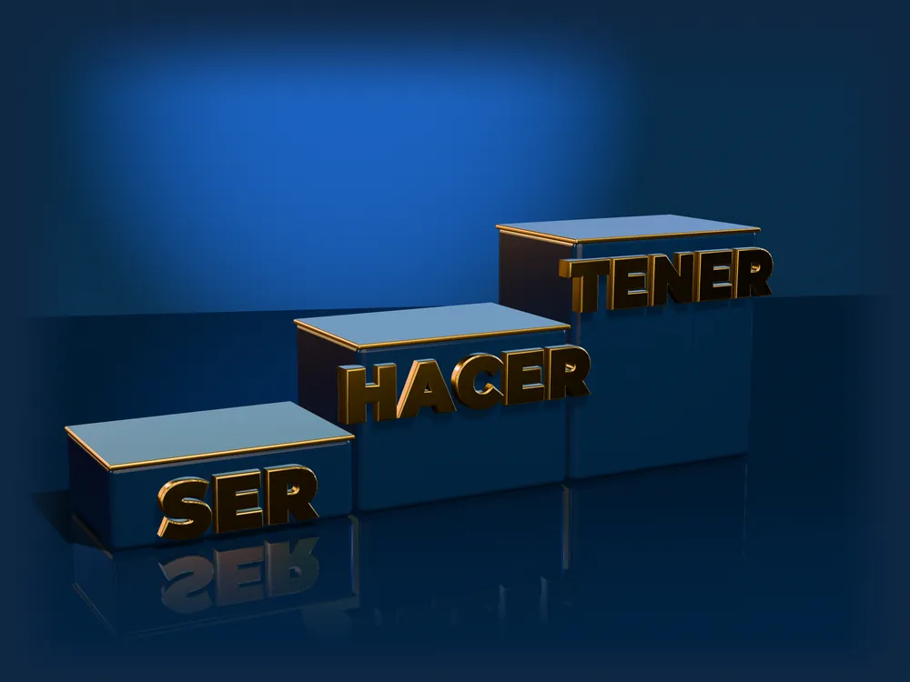 Tres escalones azules con las palabras SER, HACER y TENER en letras doradas en 3D